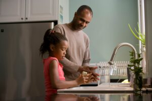 A parent and child washing dishes