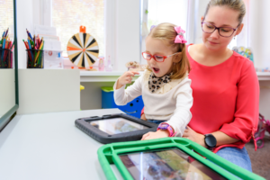 A parent with a child sitting on their lap. They are looking at iPads.