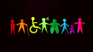 Rainbow-colored paper-cut figures representing people of different ages, body types, and disabilities, including a wheelchair user, a person using a white cane, a person signing, and an amputee, displayed against a black background.